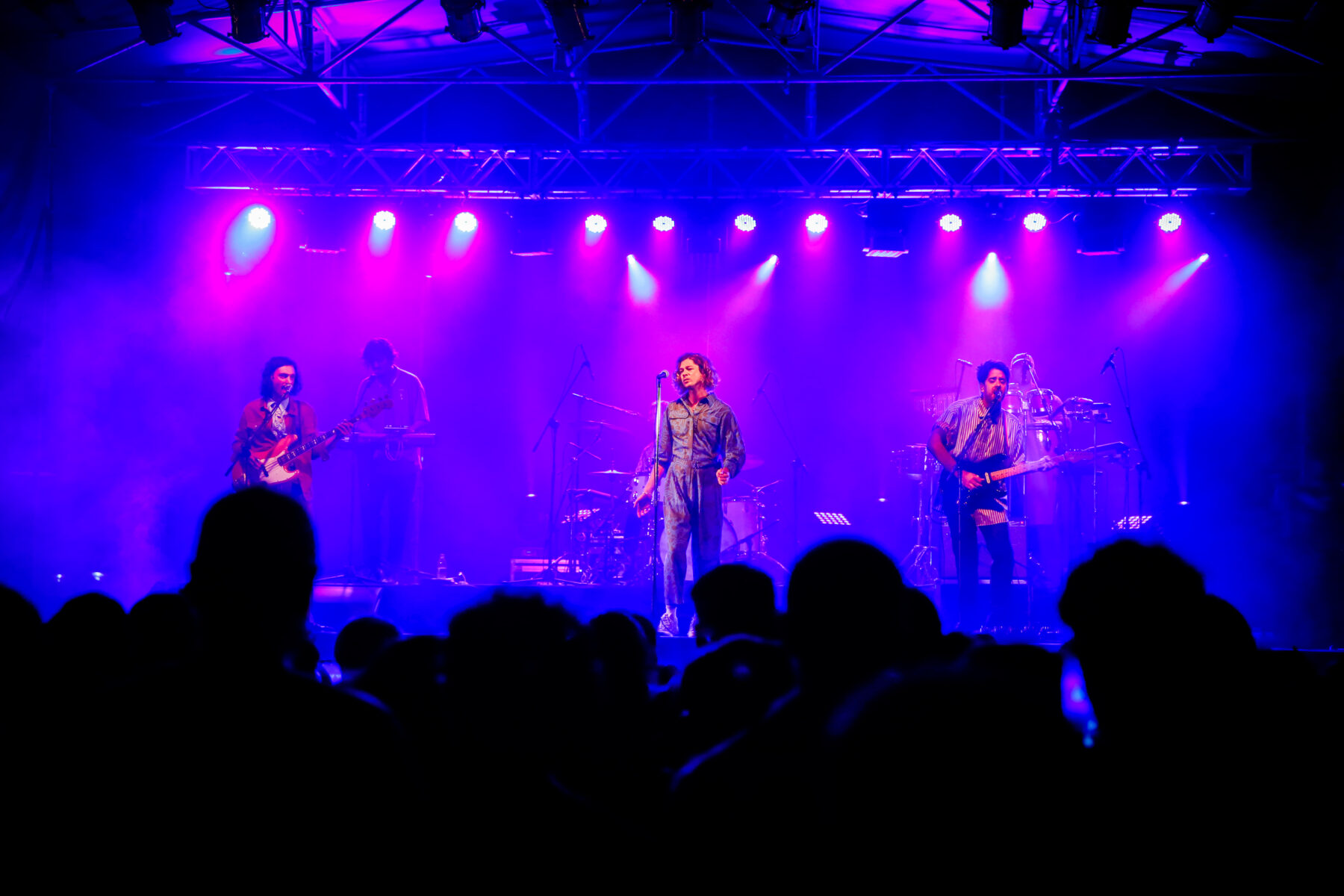 Bandalos Chinos performing on a blue-lit stage before a crowd