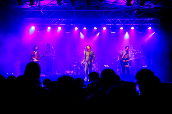 Bandalos Chinos performing on a blue-lit stage before a crowd