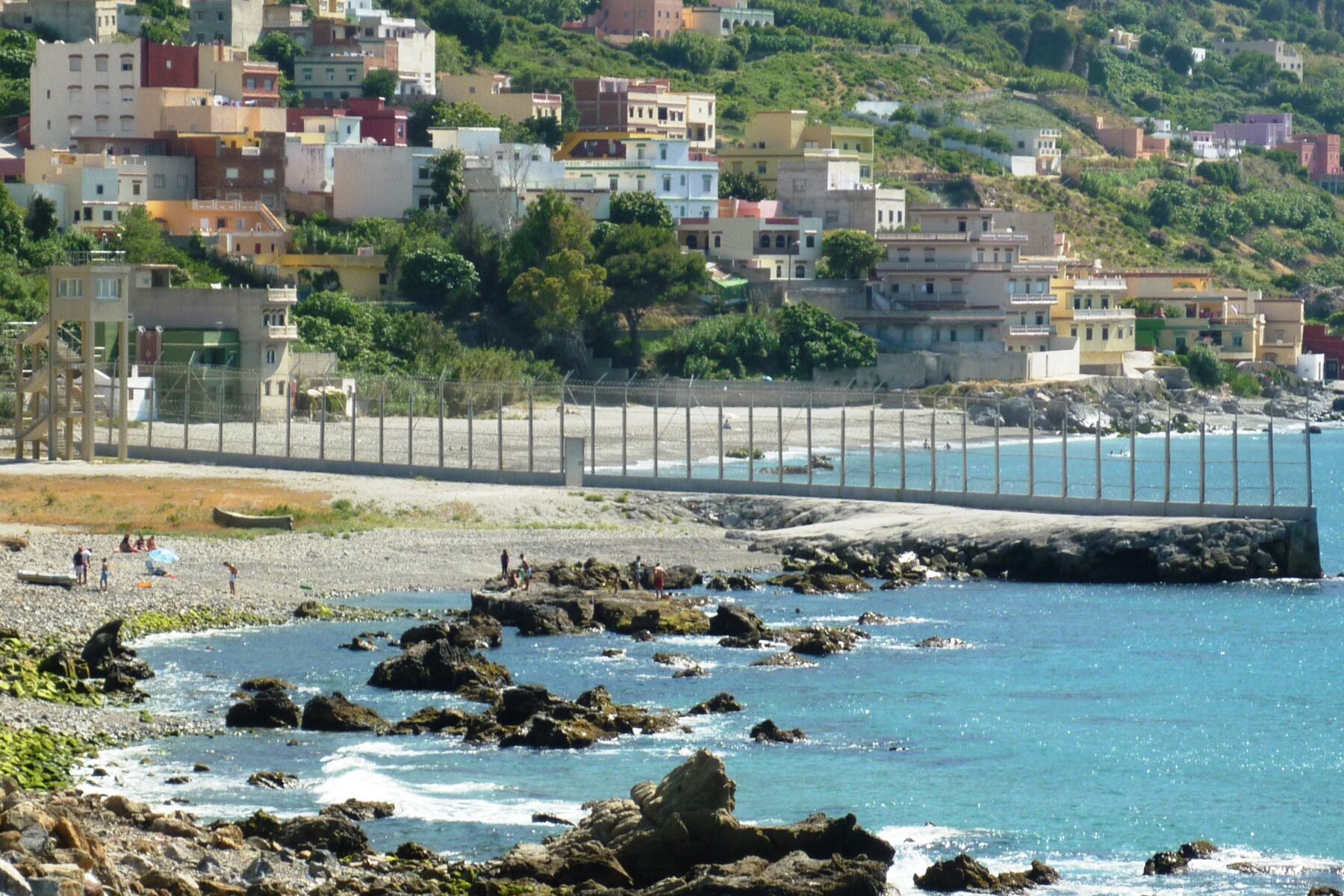 Ceuta migrant crossing — the border fence between Morocco and the Spanish enclave running down to the sea