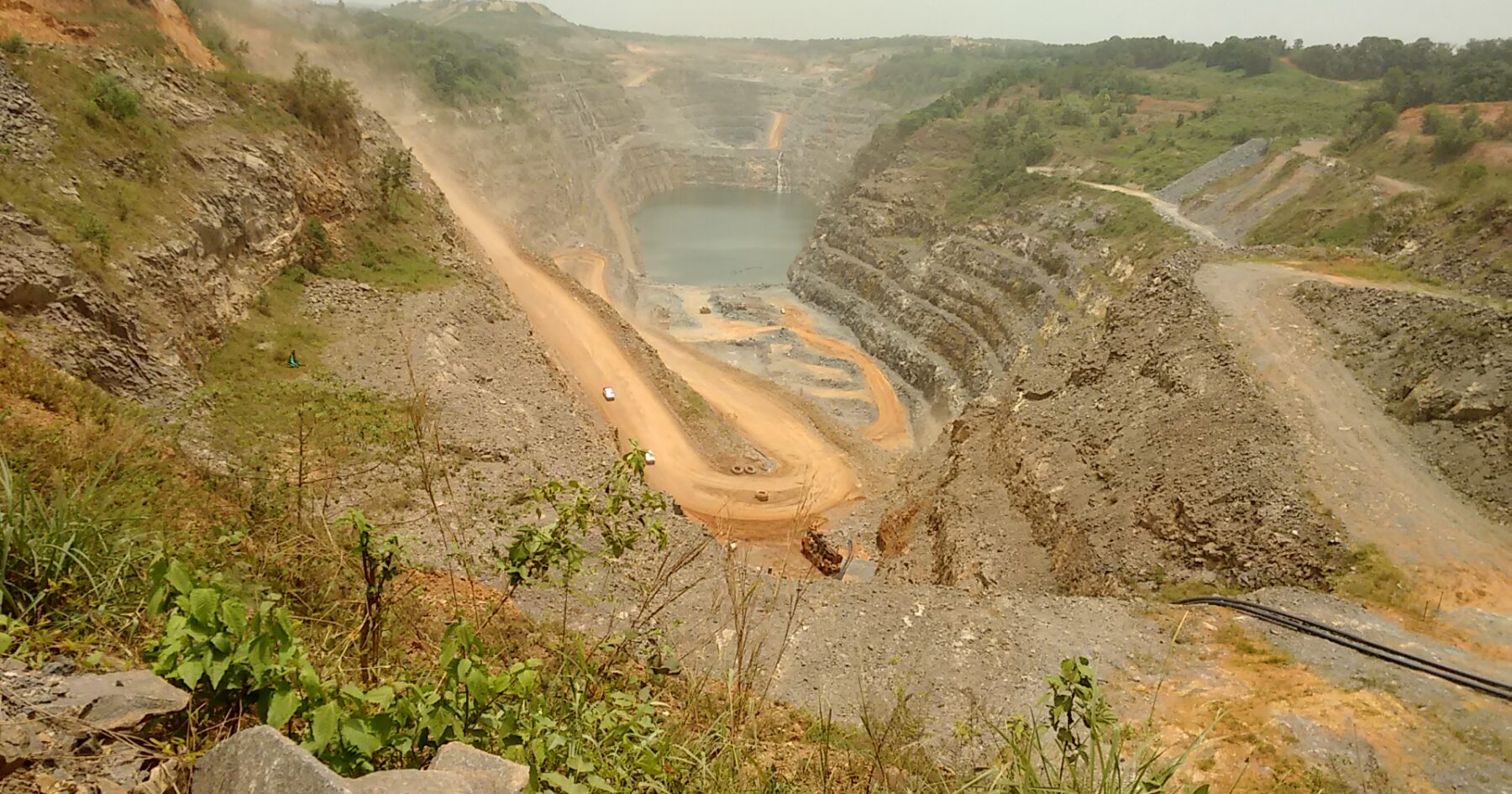 Large open-pit mine with water and dirt roads