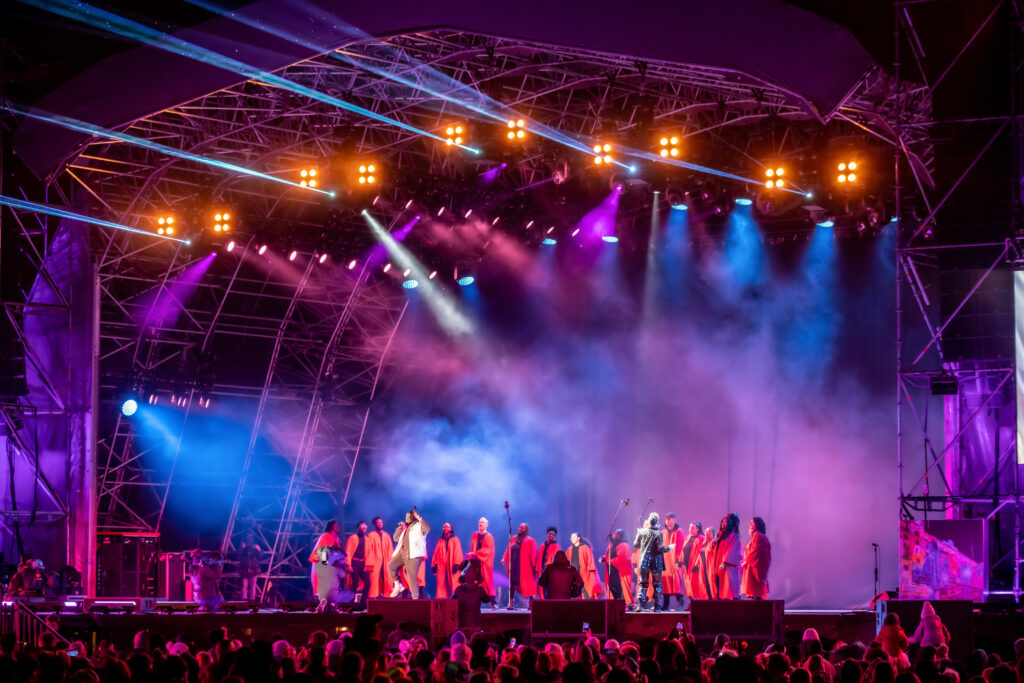Gospel choir in robes performing on an open-air festival stage at night