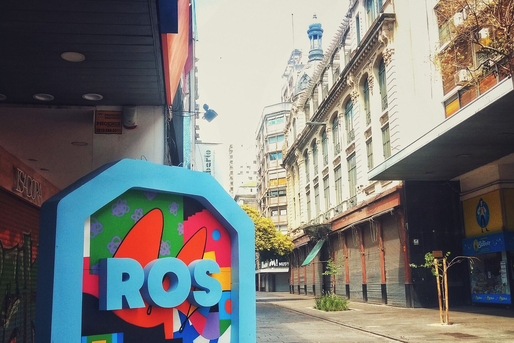 Street with 'ROS' sign, old buildings, closed shops