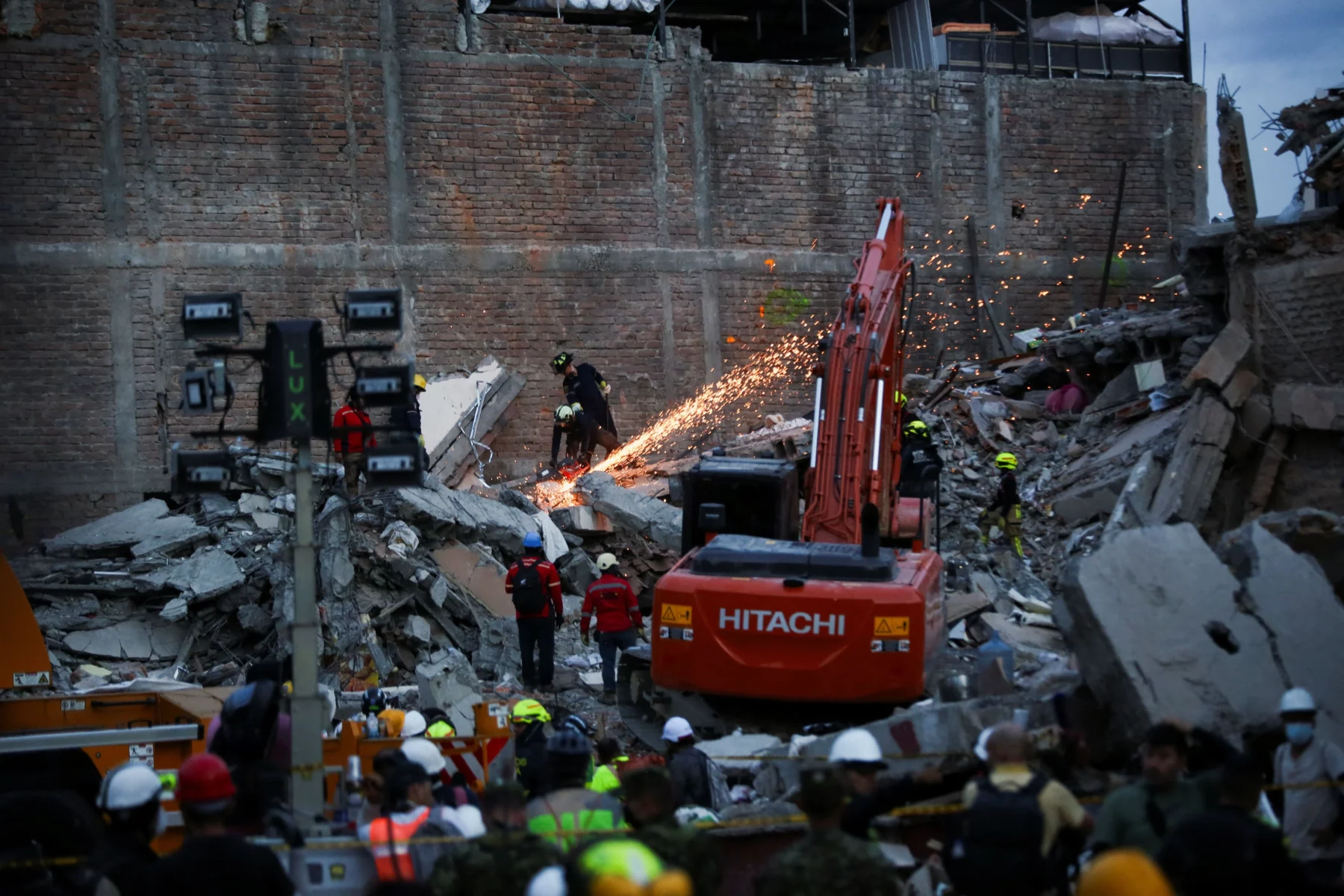 Rescue workers, excavator, sparks at earthquake rubble site