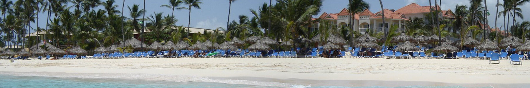 Beach with palm trees, umbrellas, and resort buildings