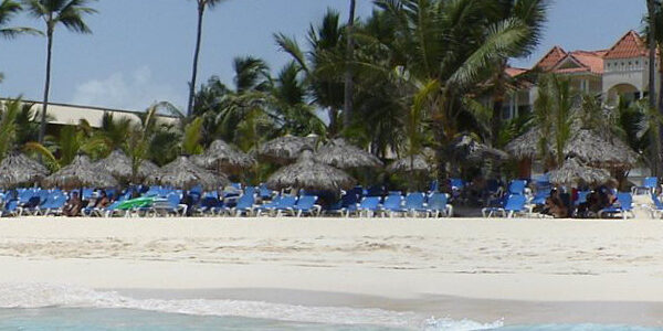 Beach with palm trees, umbrellas, and resort buildings