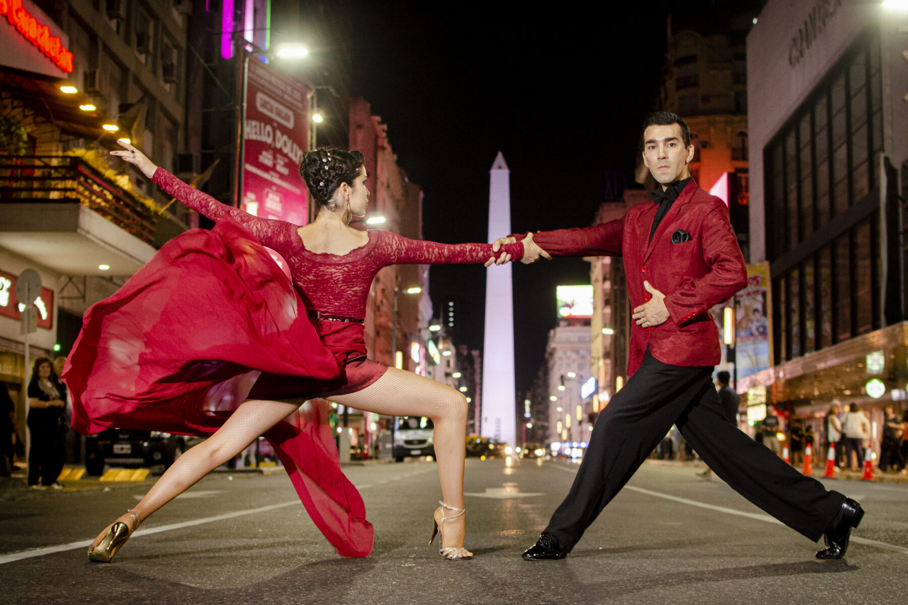 Two tango dancers in red on a city street at night
