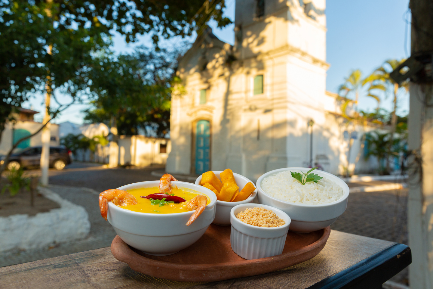 Brazilian food with shrimp, rice, and sides, church in background