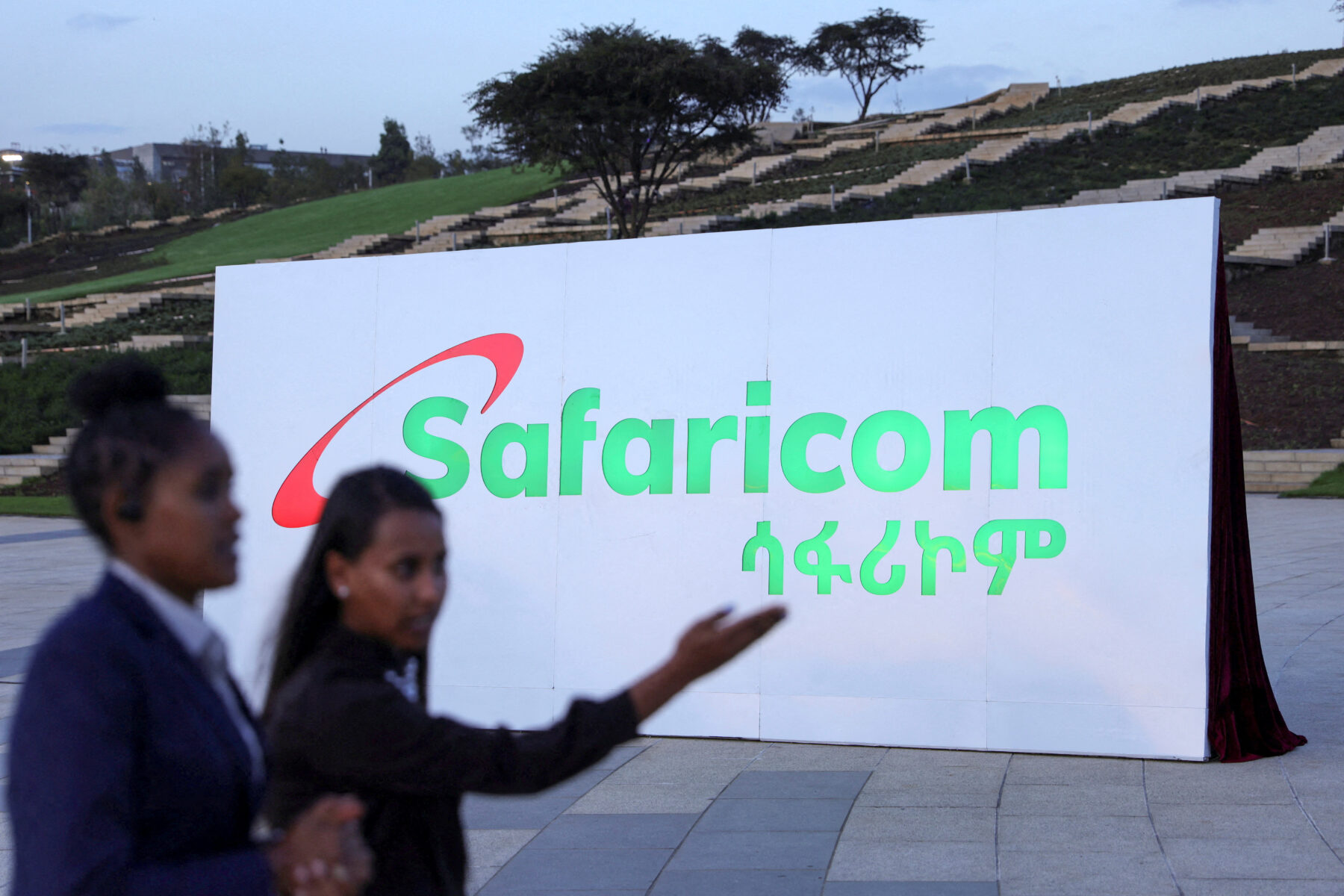 Safaricom Ethiopia employees walk past a billboard during the Safaricom ceremony to officially launch its operations in Ethiopia, in Addis Ababa