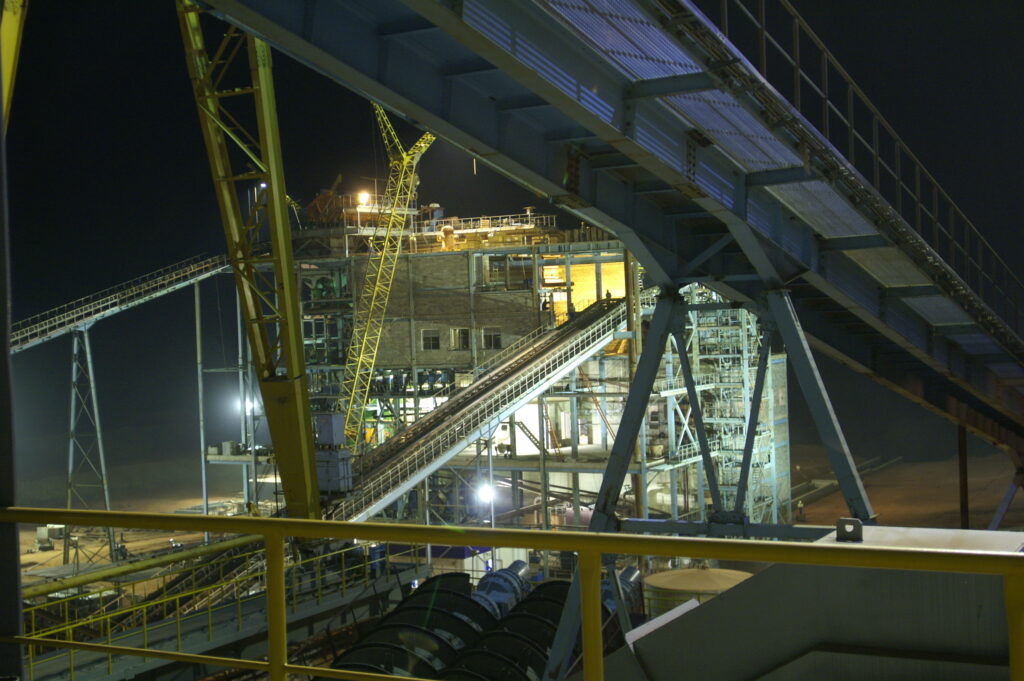 Industrial mining facility at night with conveyors and structures