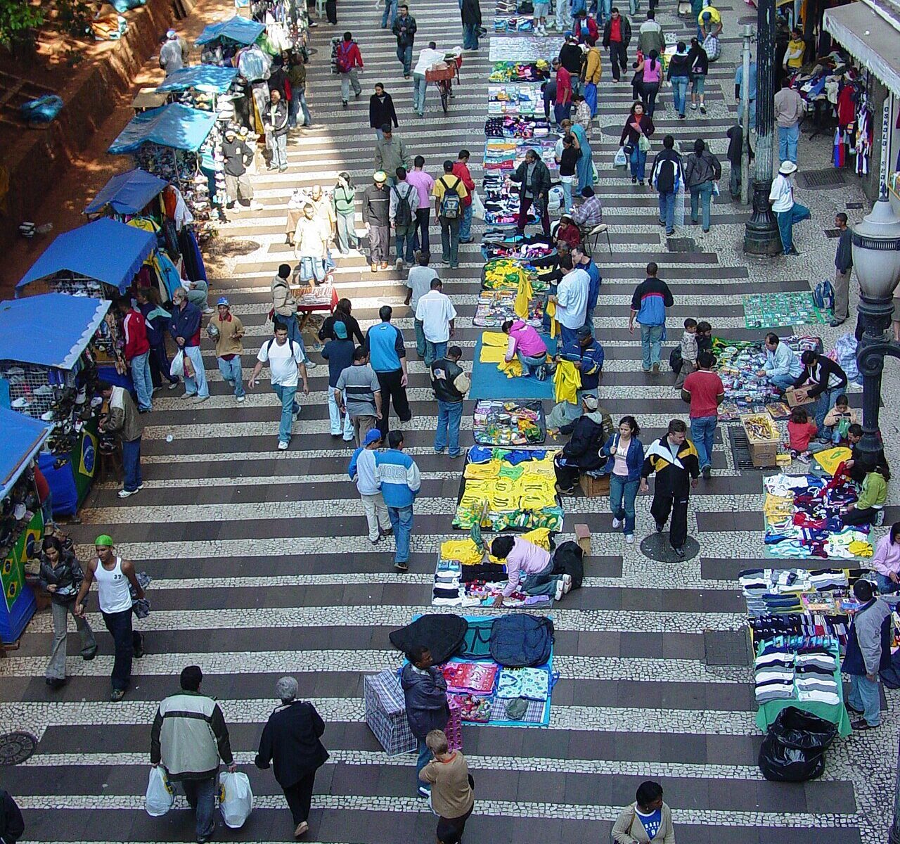 A busy outdoor market with many vendors and shoppers