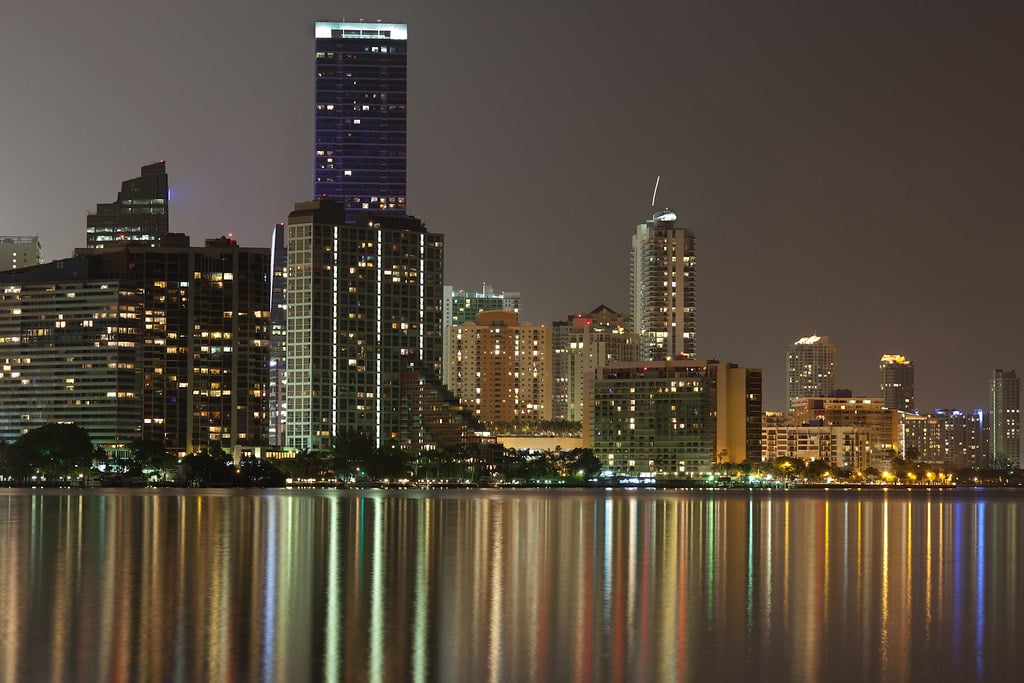 The Brickell skyline in Miami at night, towers reflected in the water