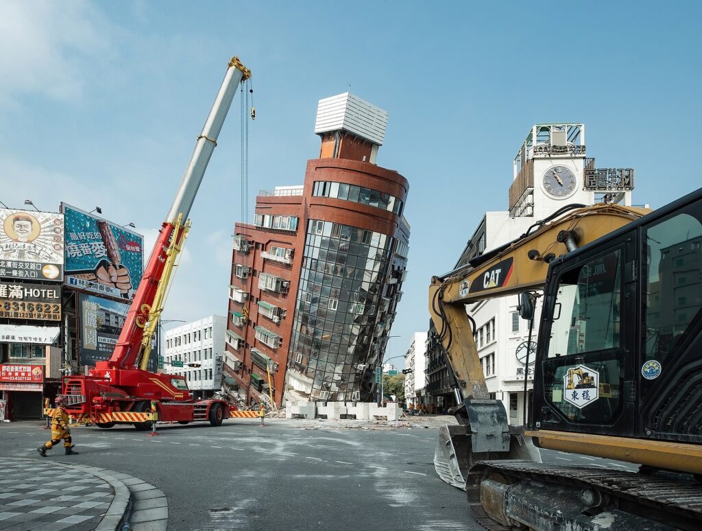 Tilted building, crane, excavator, and debris after quake