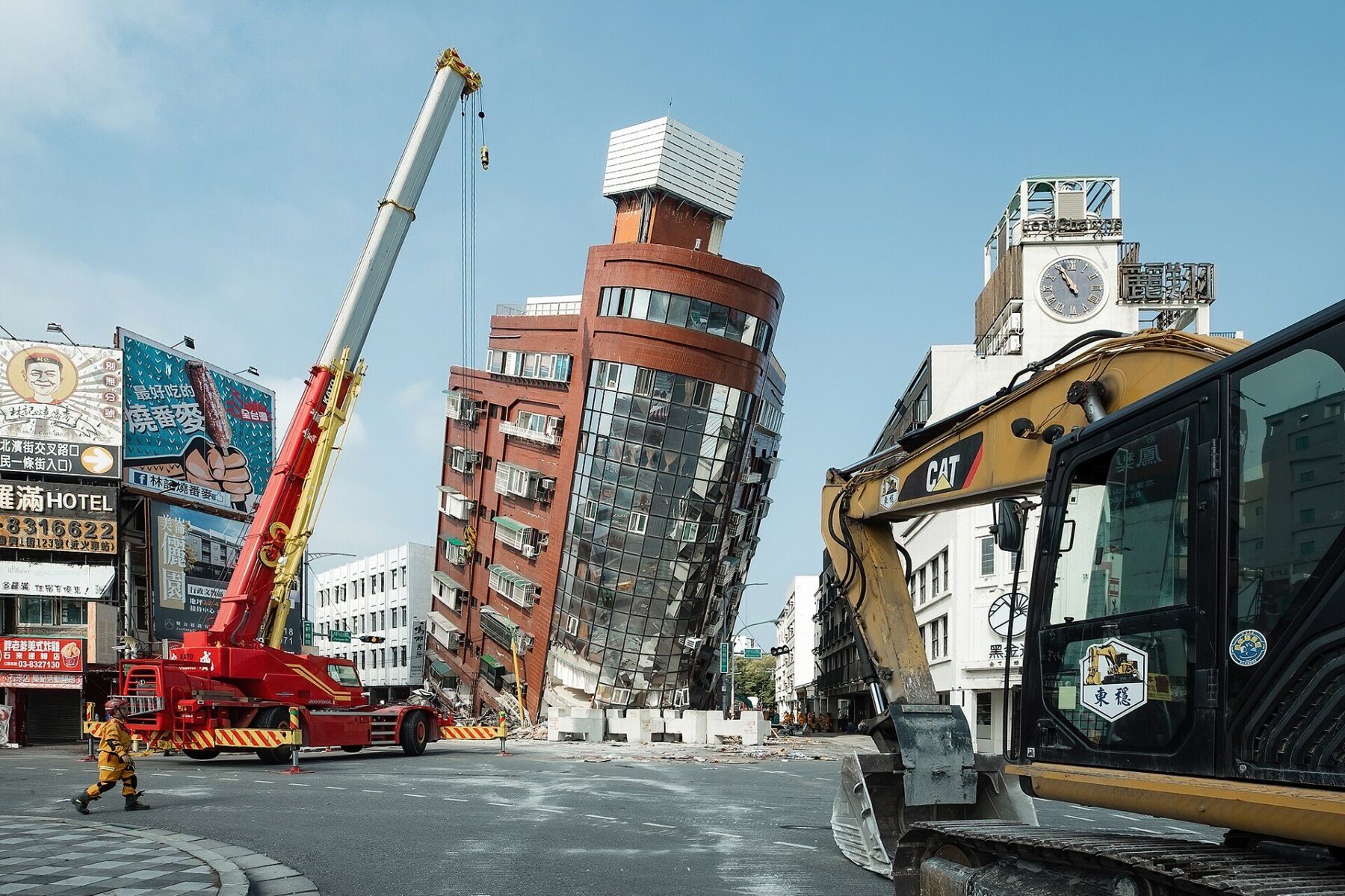 Tilted building, crane, excavator, and debris after quake