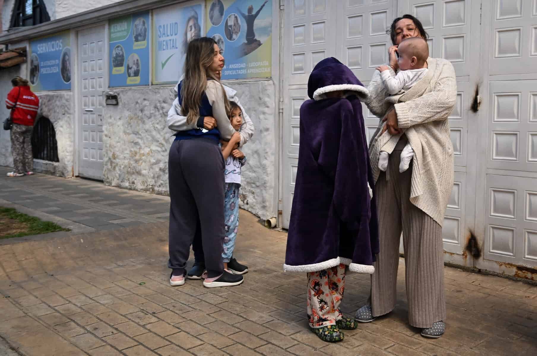 Residents in the street after the Colombia earthquake, some in pyjamas and wrapped in blankets, holding children.