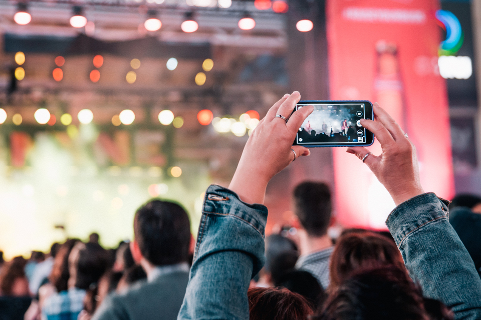 A concert audience filming a lit stage on a phone