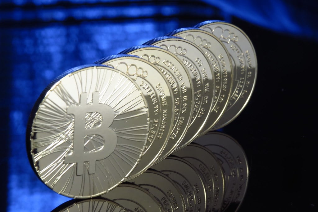A row of physical bitcoin coins on a blue background, illustrating the crypto market wrap