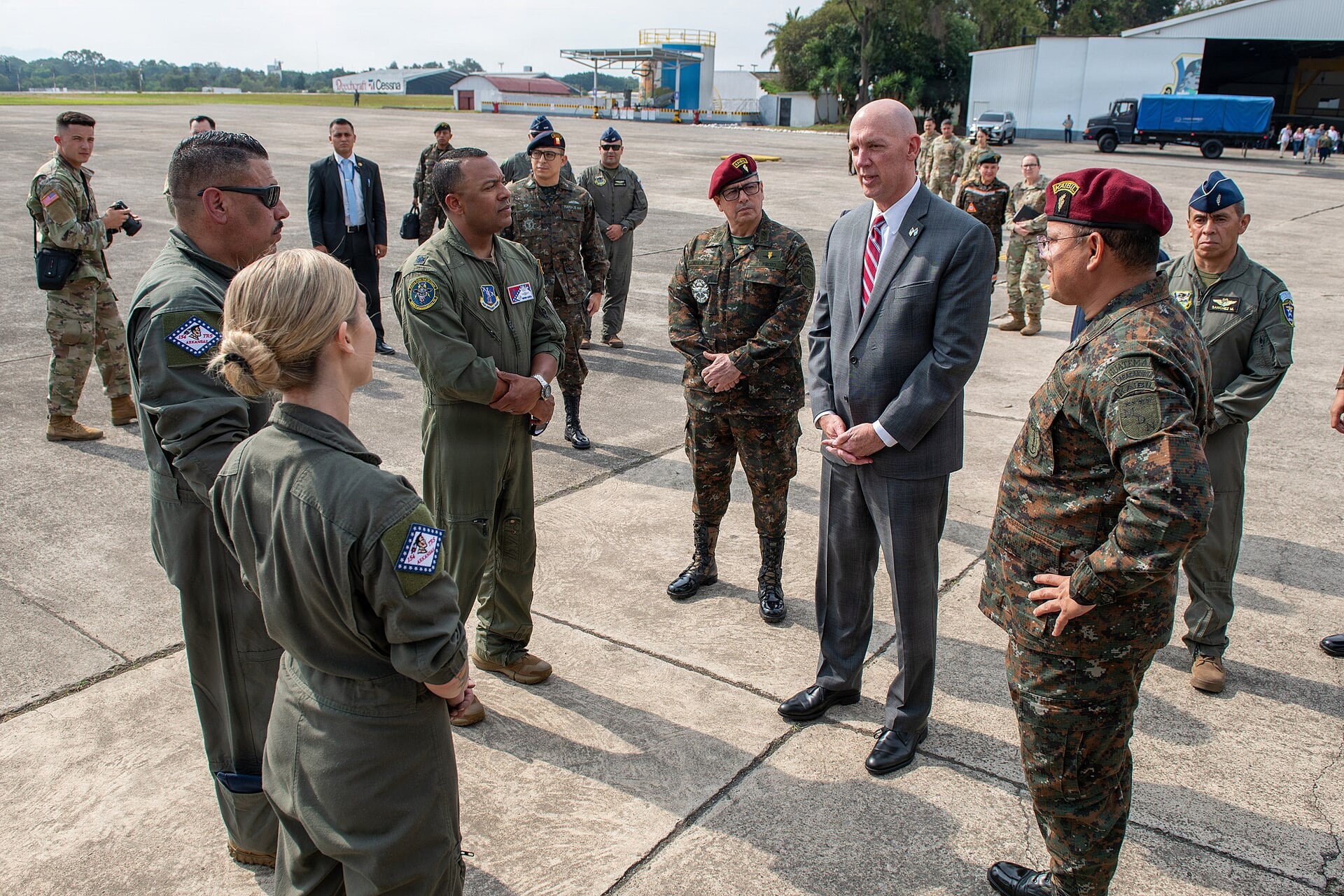 US Air National Guard aircrew and Guatemalan army officers in red berets talk on an airfield apron