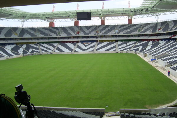 An empty football stadium bowl with green pitch and tiered seating