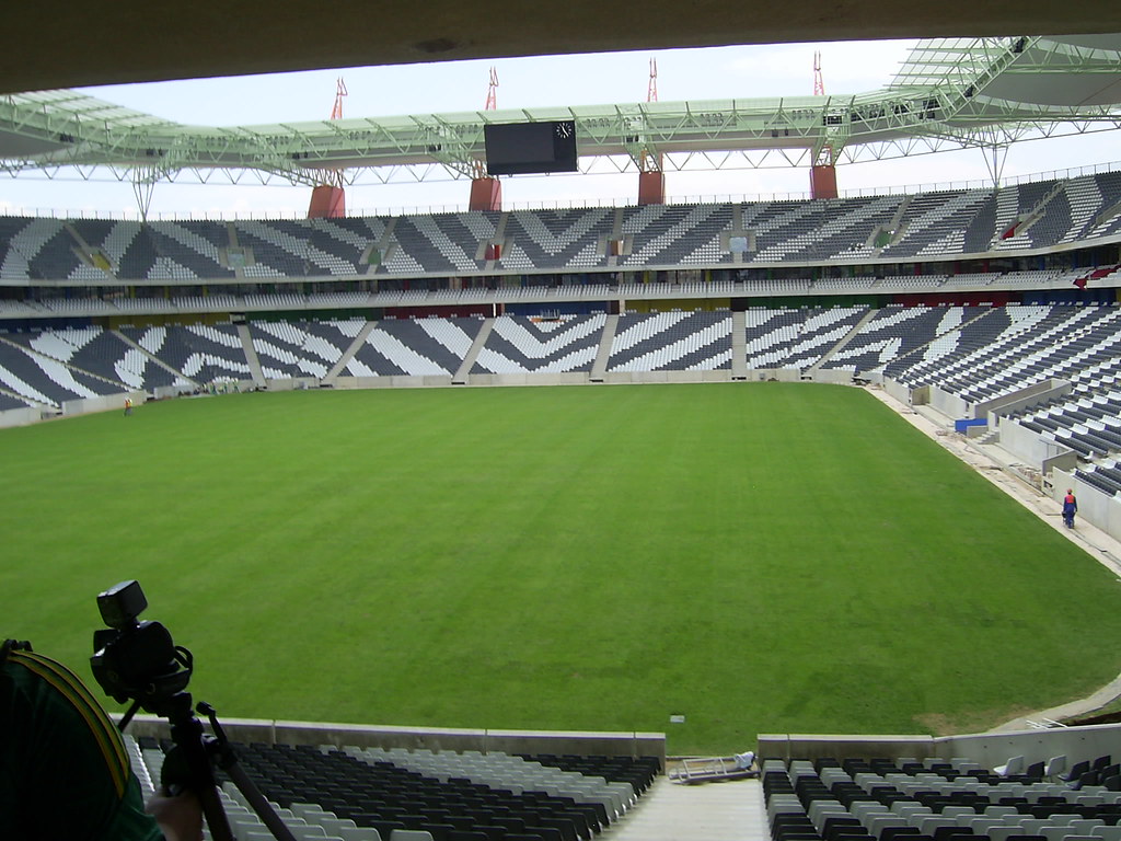 An empty football stadium bowl with green pitch and tiered seating