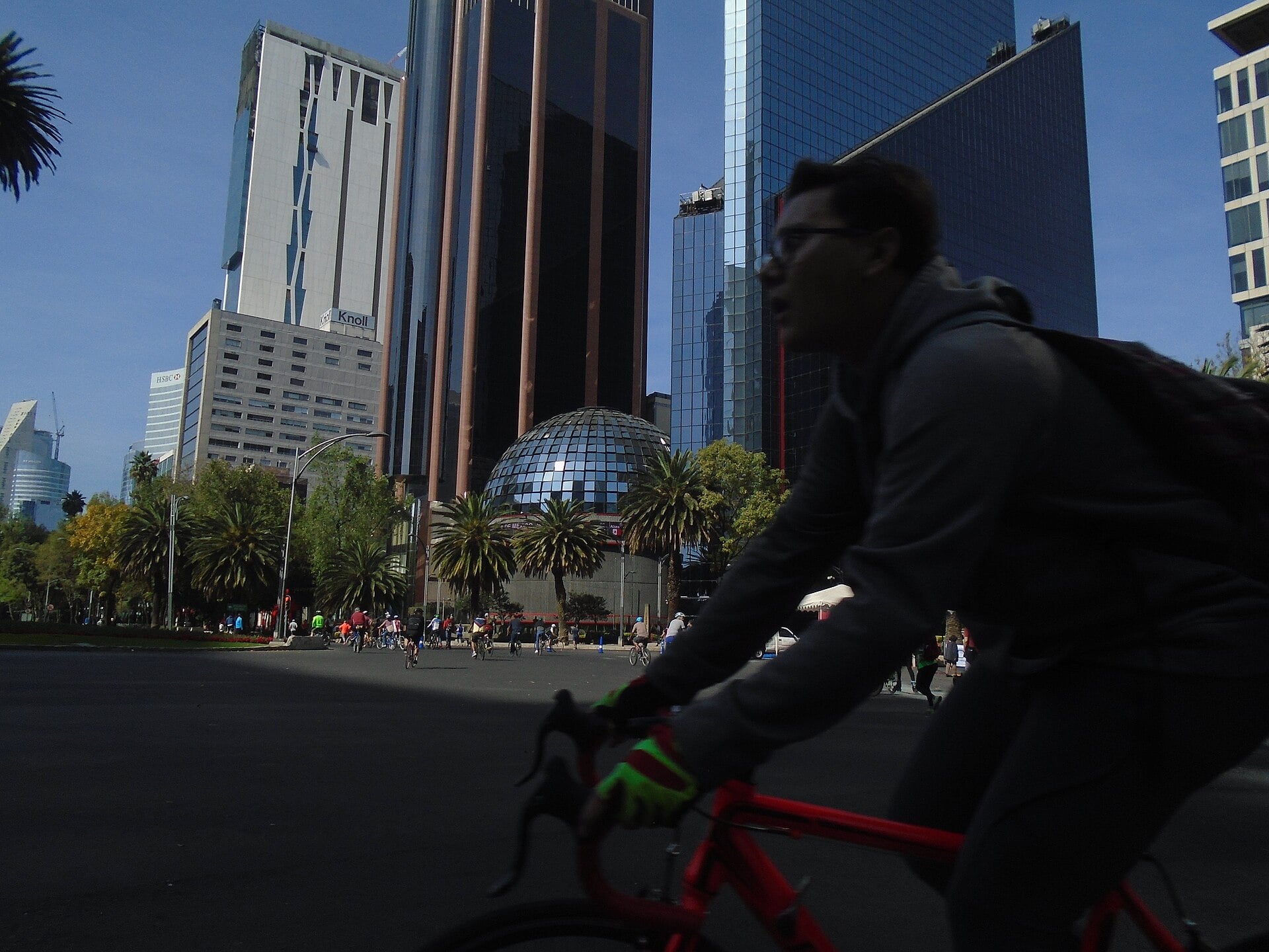 A cyclist rides past the domed Bolsa Mexicana de Valores building and office towers on Paseo de la Reforma in Mexico City