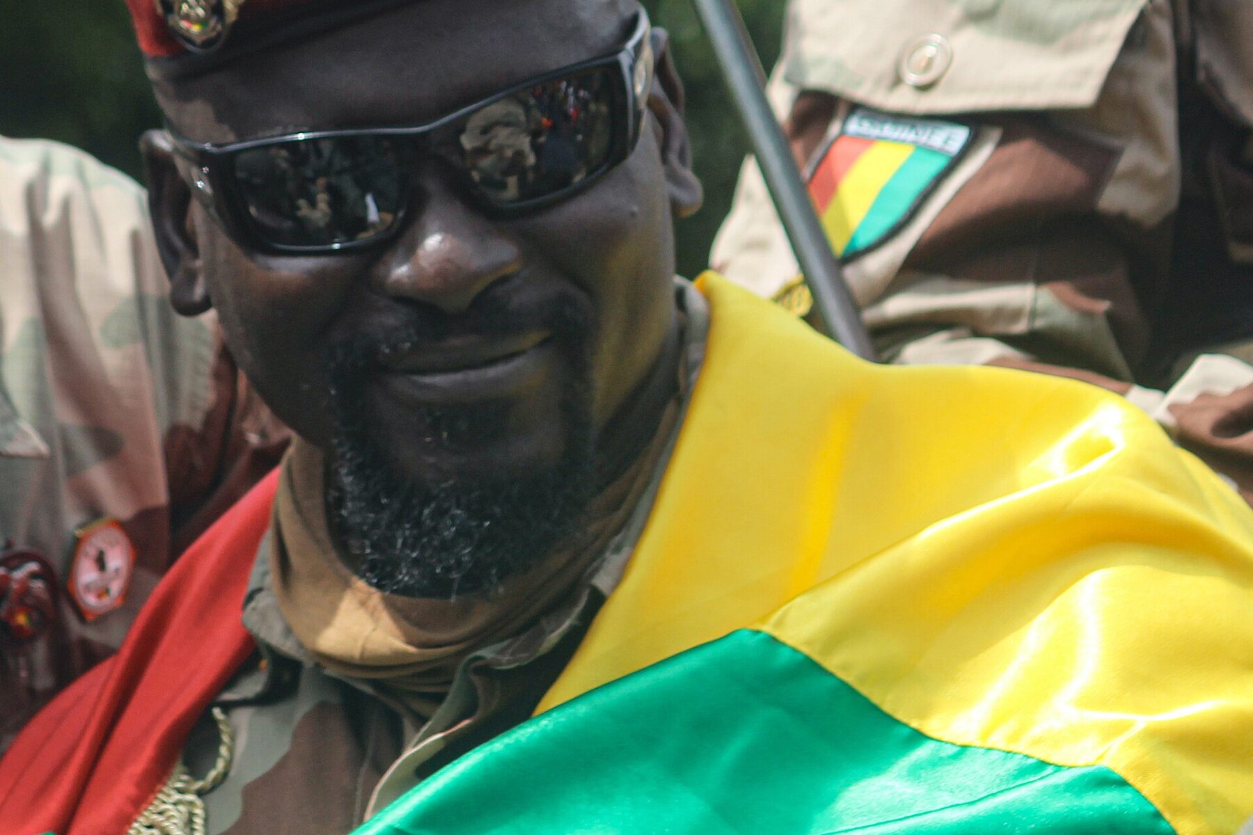 Man in sunglasses with Guinea flag, military uniform