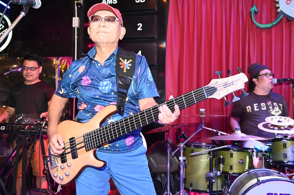 A bassist, keyboard player and drummer performing on a small stage