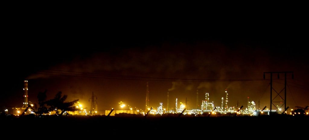 An oil refinery complex lit up at night; Guyana imports all its refined fuel despite producing crude offshore