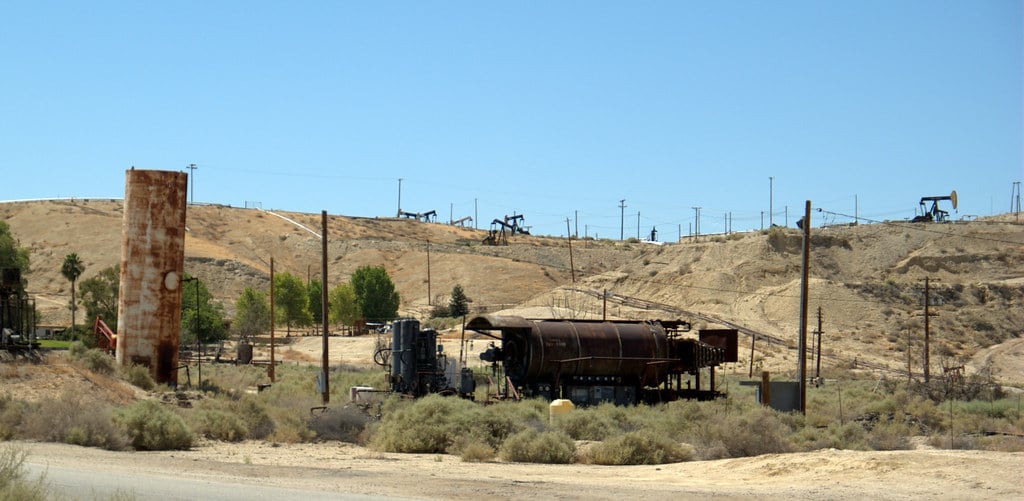 Pumpjacks and tanks across dry scrubland at an oilfield