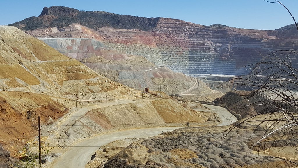 Terraced benches of a large open-pit copper mine under a clear sky