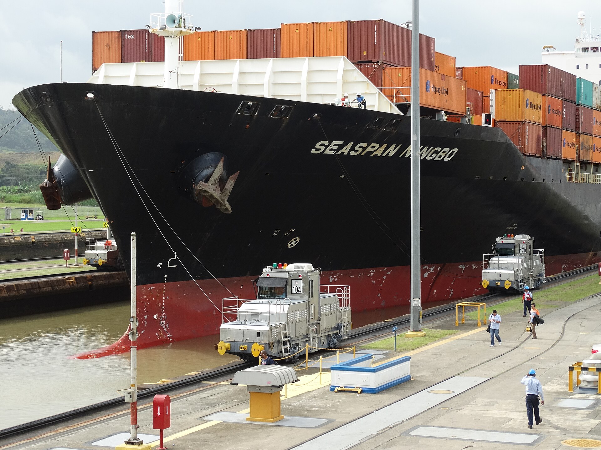 Panama Canal transits &mdash; locomotives guide a container ship through the Miraflores Locks