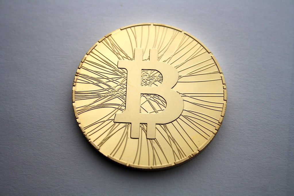 Physical gold bitcoin coin on a grey surface