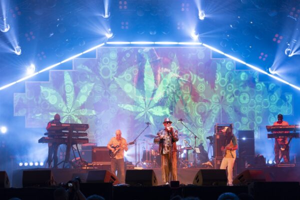 A reggae band performs on a colourful festival stage.