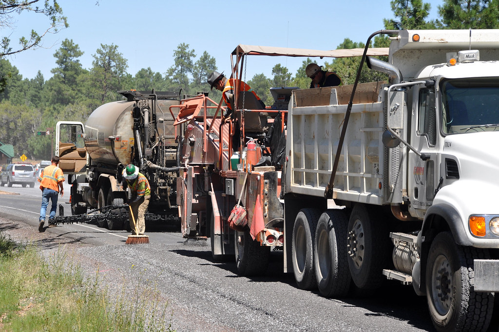 Road crew and a dump truck resurfacing a two-lane highway