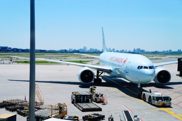 An Air Canada Boeing 777 parked at an airport gate with a city skyline behind, ahead of the airline's new Guatemala City to Toronto route