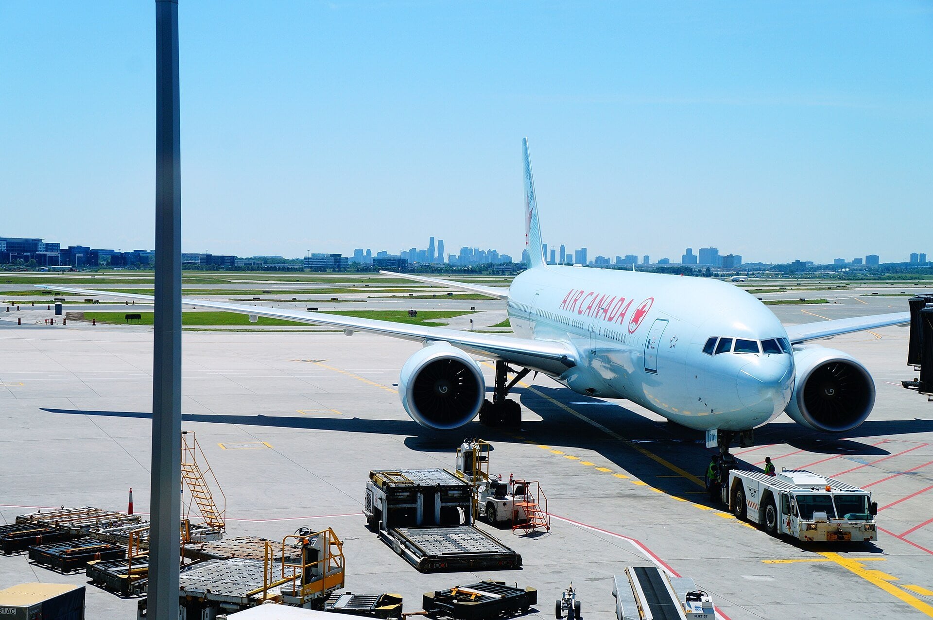 An Air Canada Boeing 777 parked at an airport gate with a city skyline behind, ahead of the airline's new Guatemala City to Toronto route