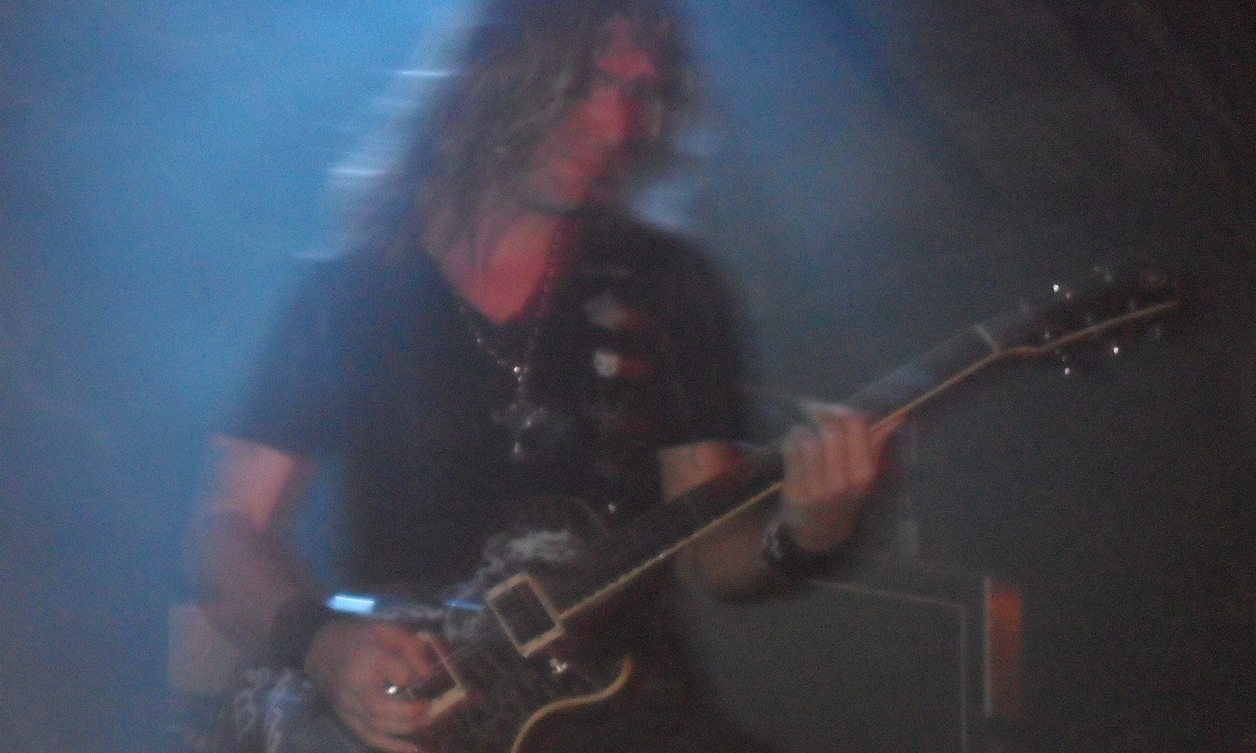 Edu Falaschi - the metal artist playing guitar under blue stage lights at a live concert