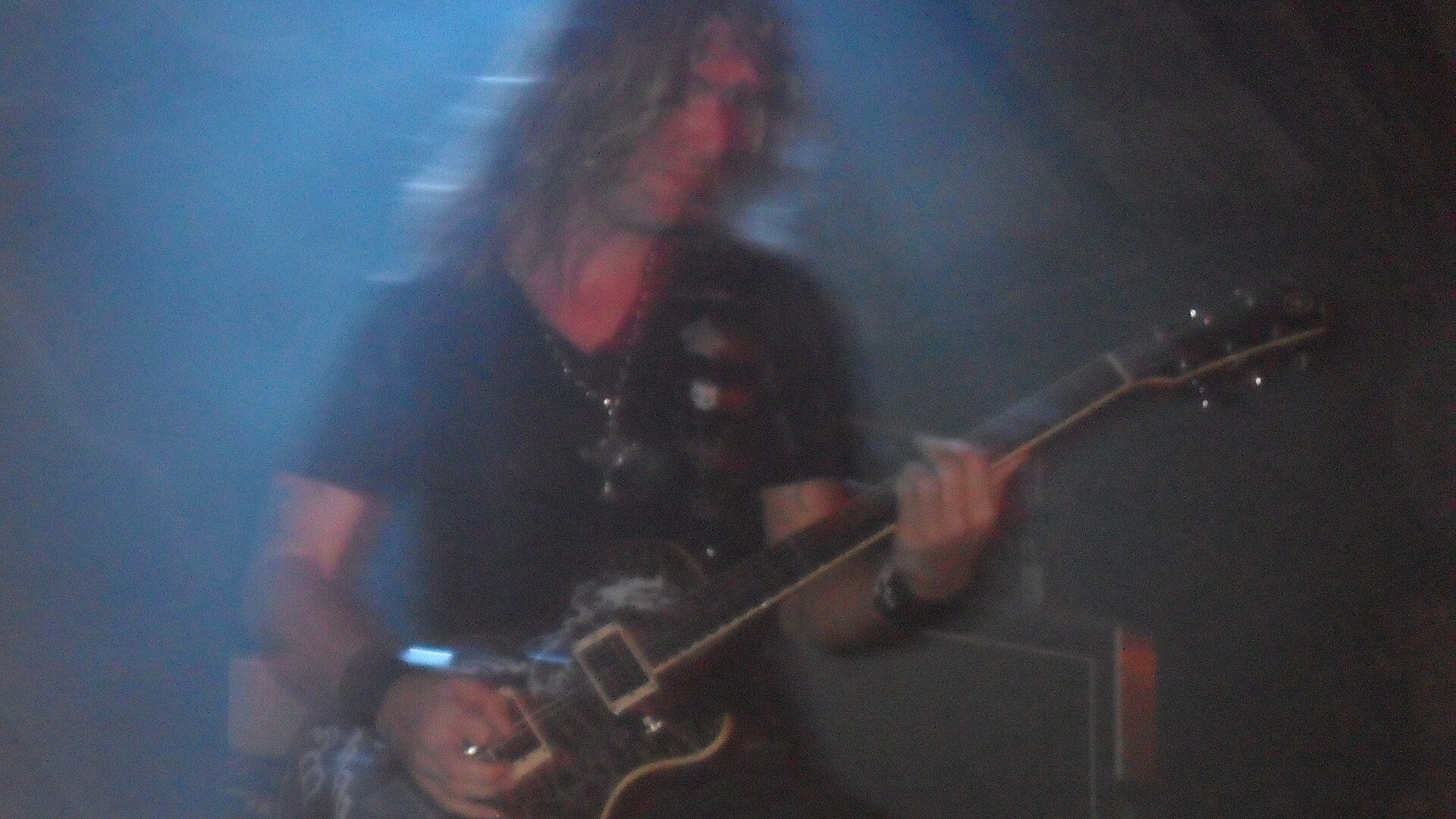 Edu Falaschi - the metal artist playing guitar under blue stage lights at a live concert