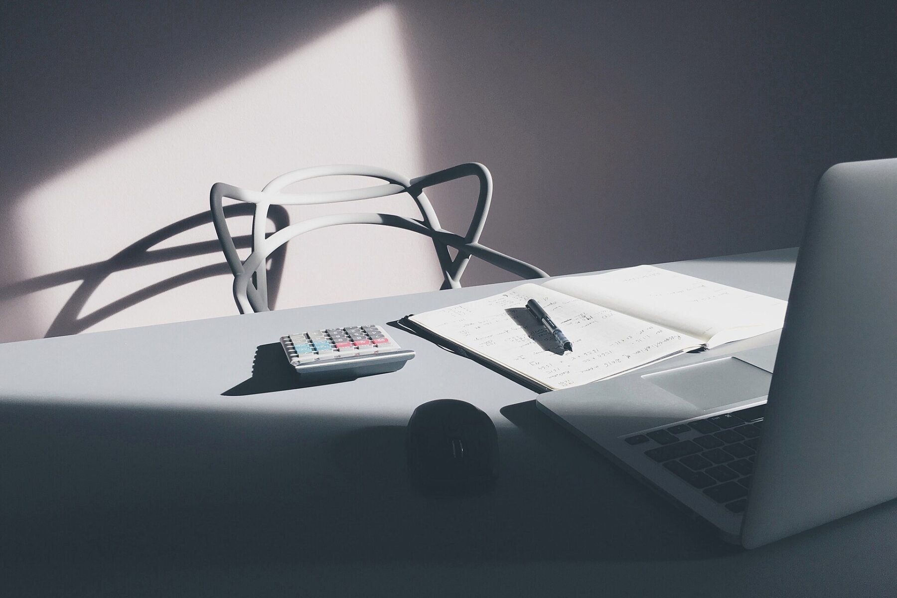 A laptop, notebook and calculator on a desk, illustrating online tax filing as Guatemala SAT pre-fills returns from e-invoice data