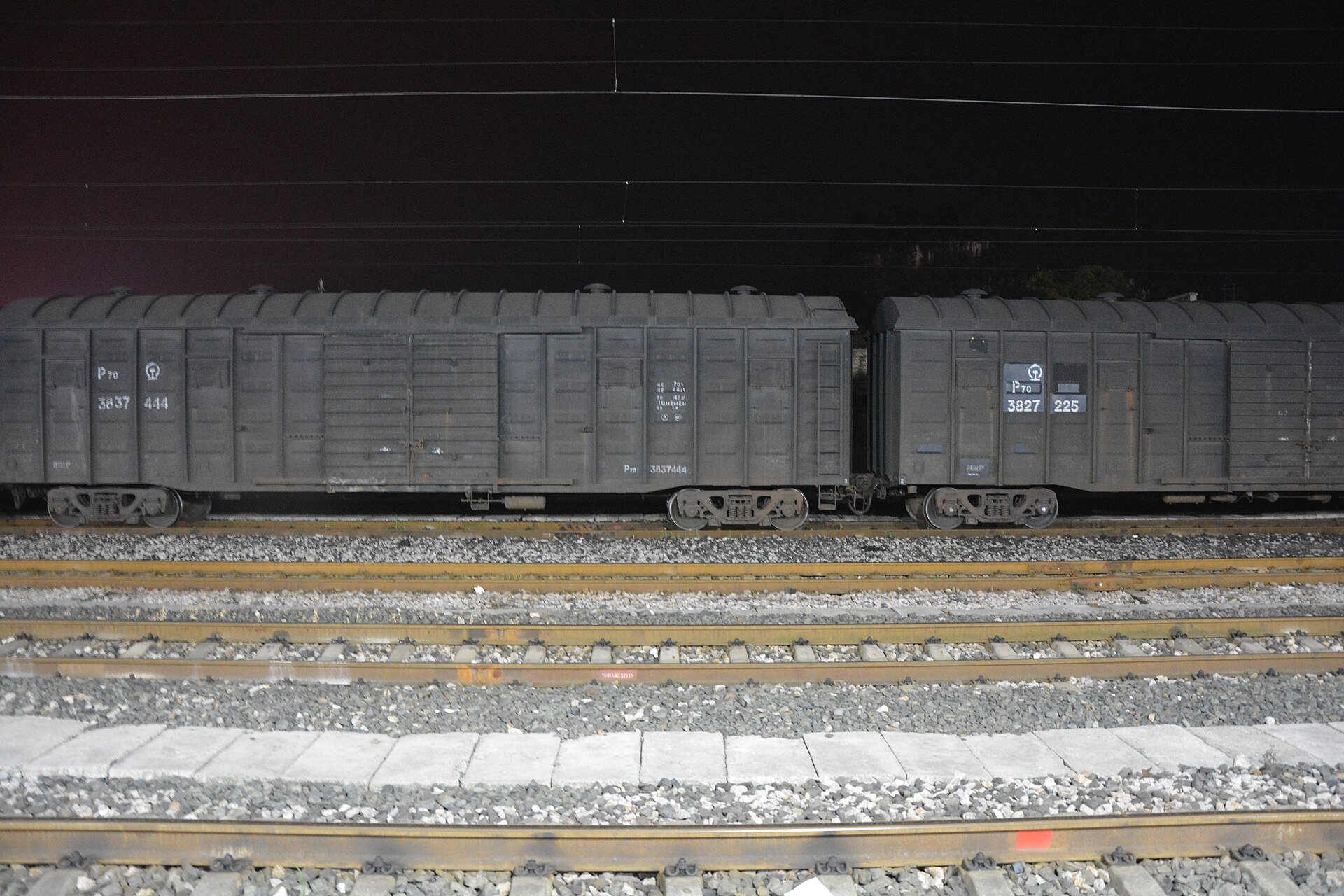 Rumo rail freight context - covered freight wagons parked on railway tracks at a station at night