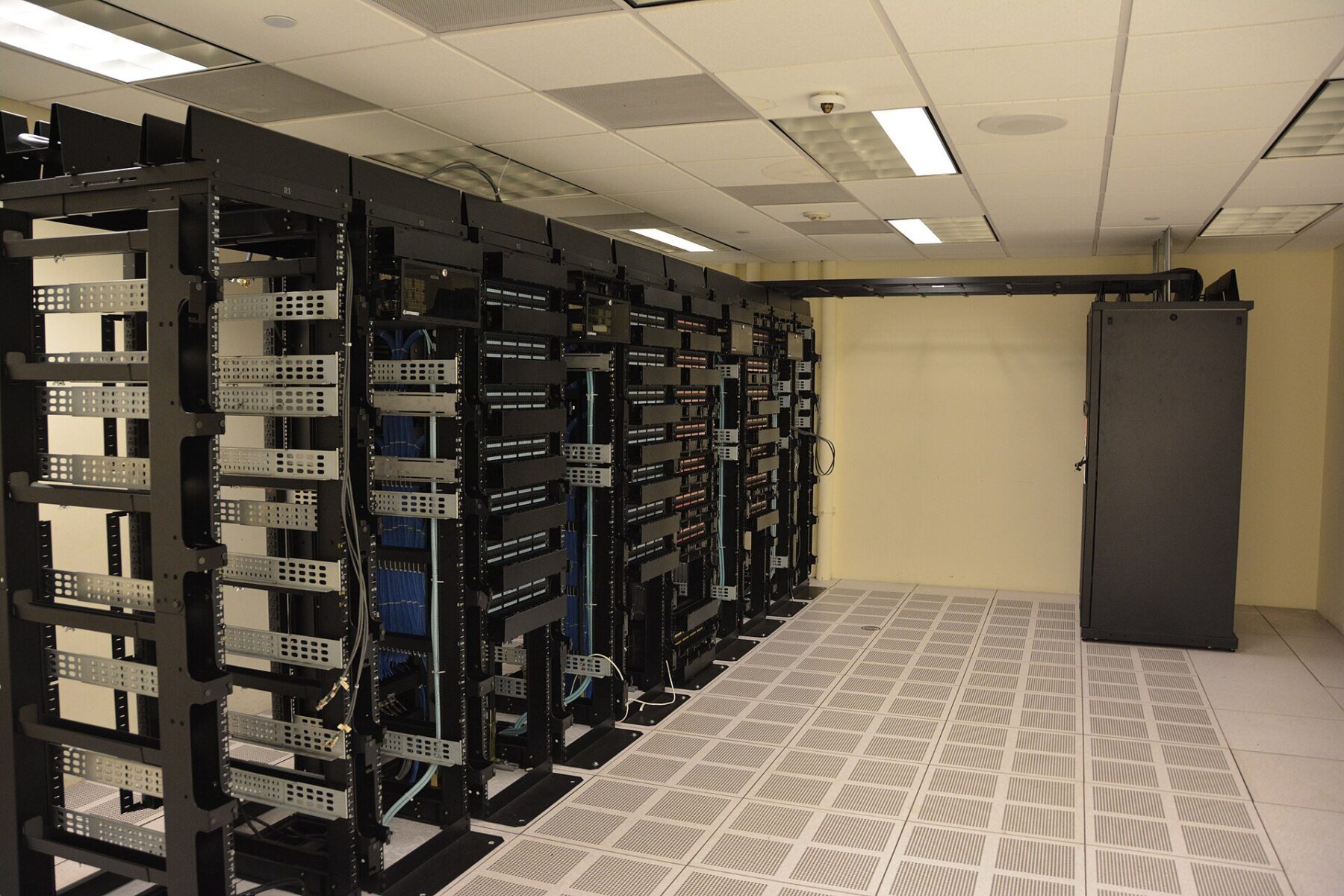 Mexico AI servers - rows of black server racks in a data center room with raised flooring