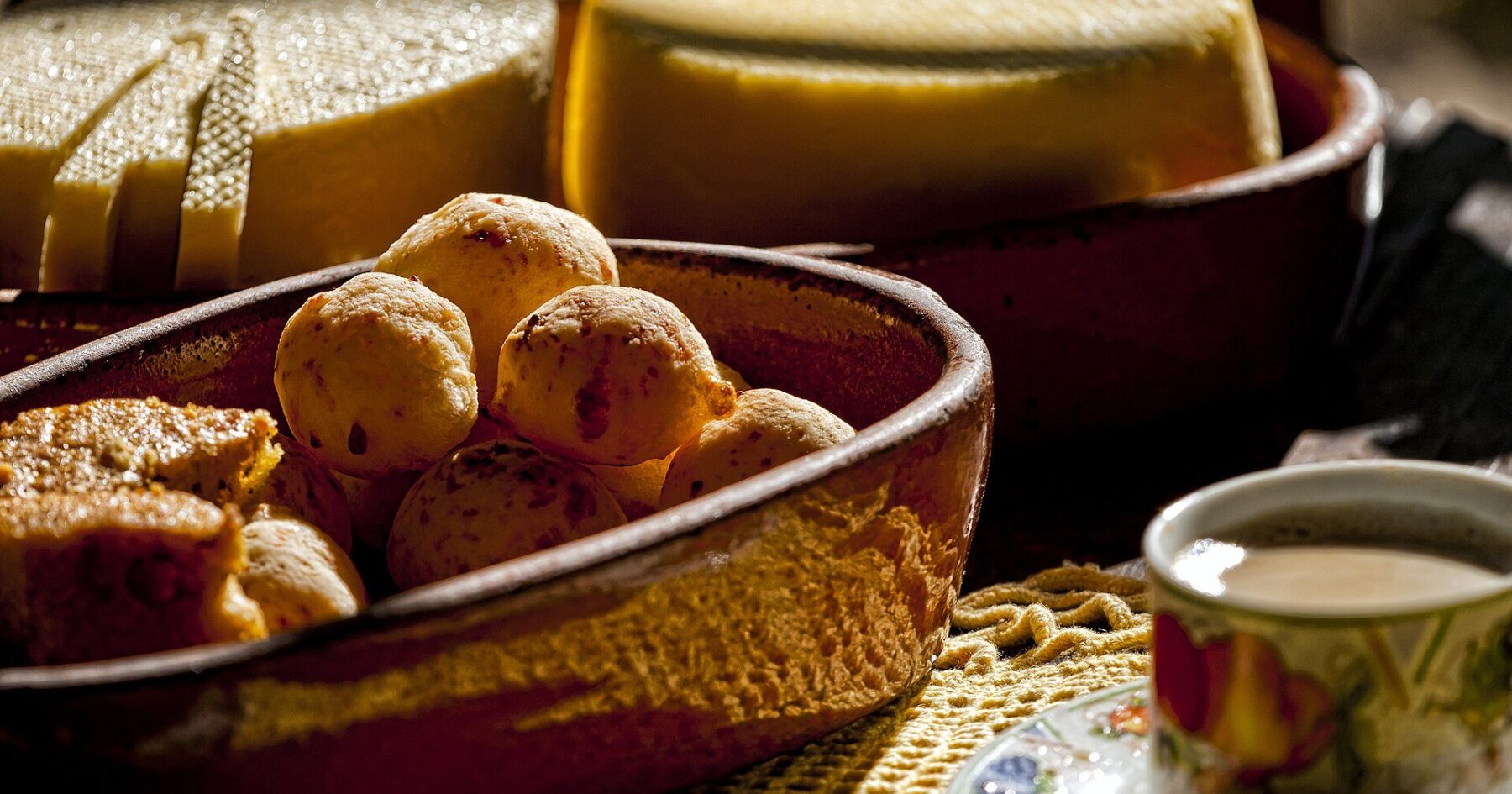 pão de queijo - a bowl of golden cheese bread rolls beside Minas cheese and coffee