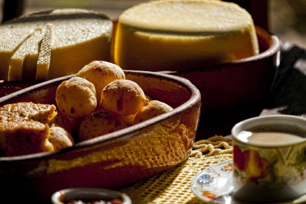pão de queijo - a bowl of golden cheese bread rolls beside Minas cheese and coffee