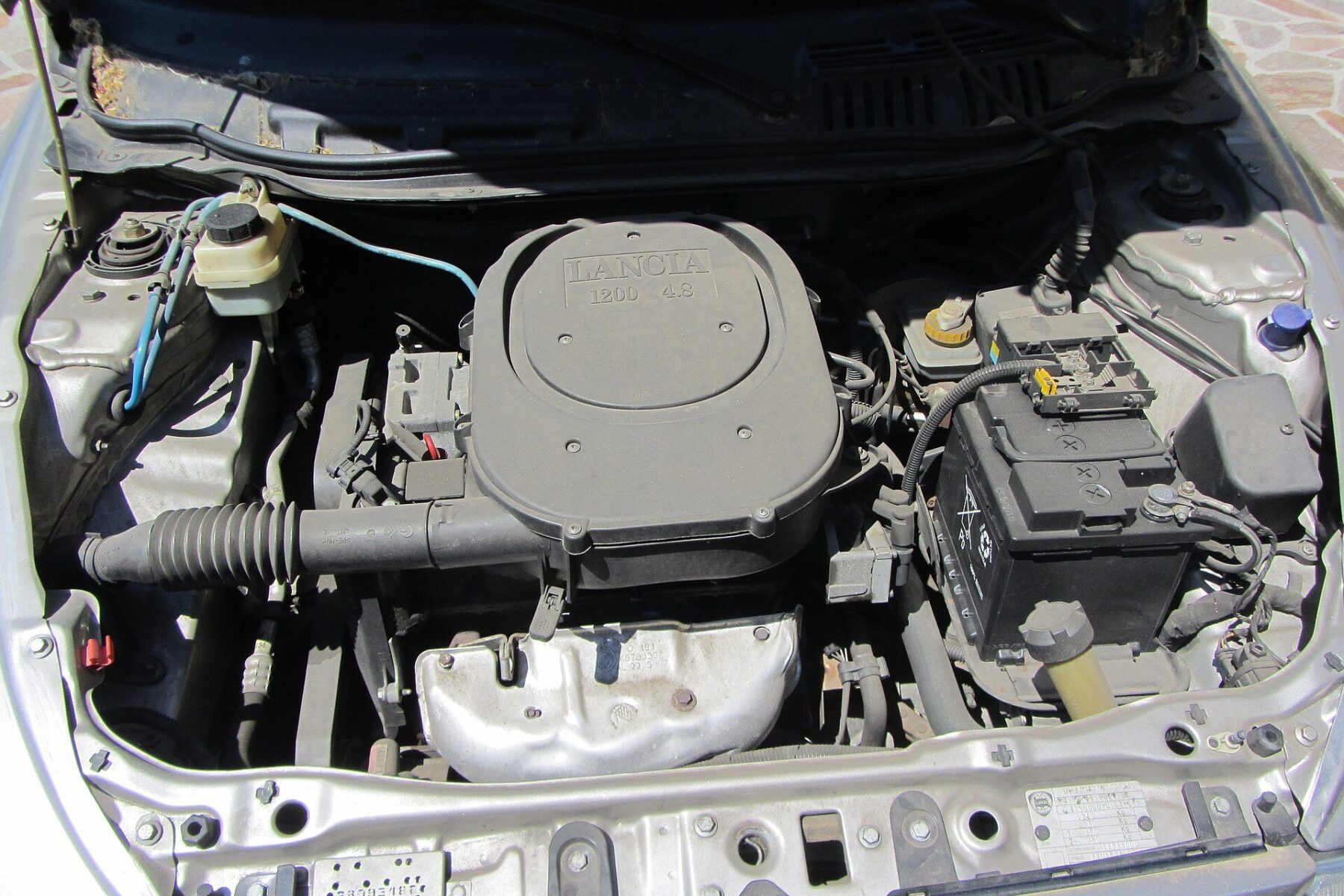 Mahle Metal Leve context - the open engine bay of a car showing the engine, battery and auto parts under the bonnet