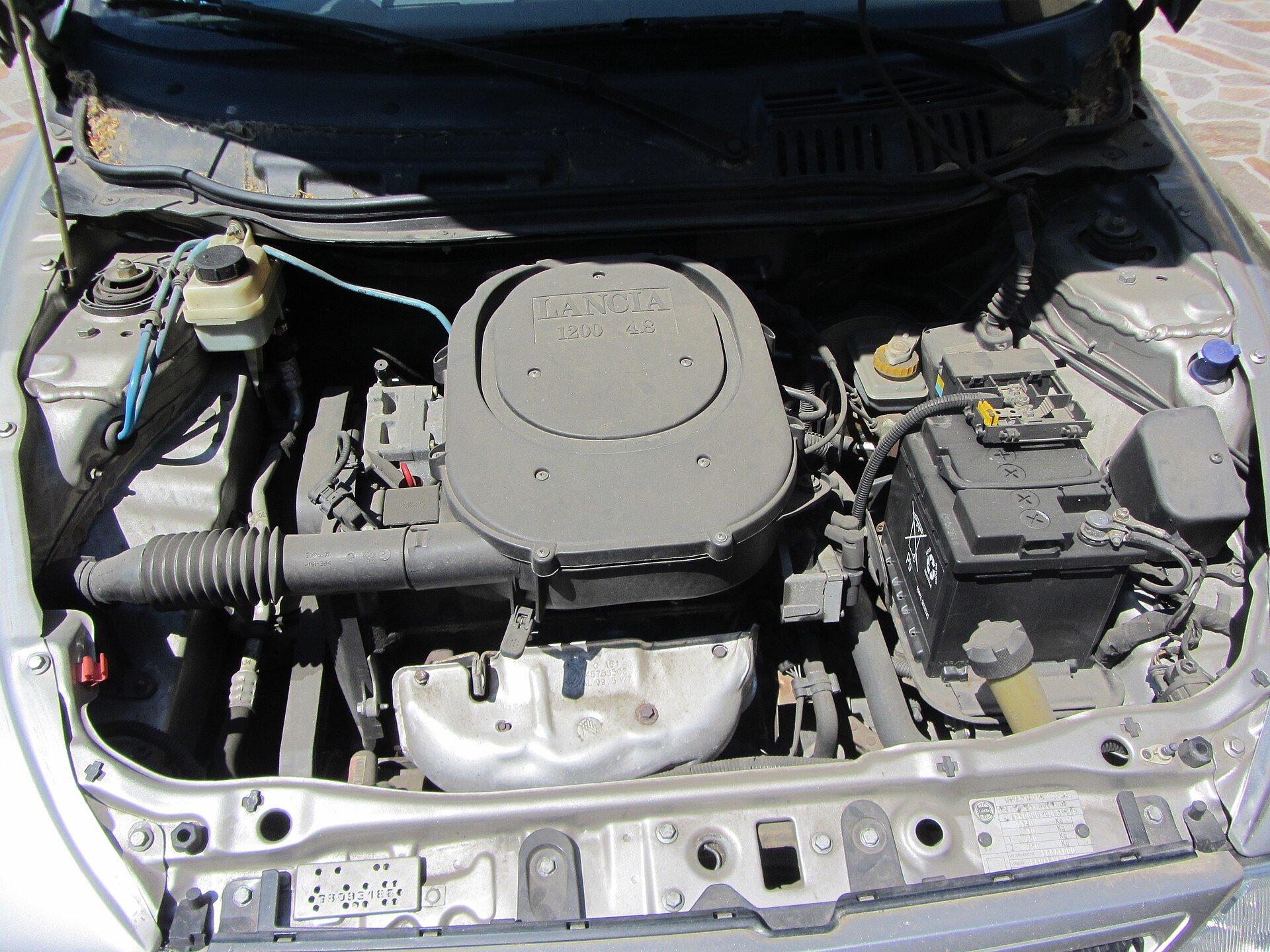 Mahle Metal Leve context - the open engine bay of a car showing the engine, battery and auto parts under the bonnet