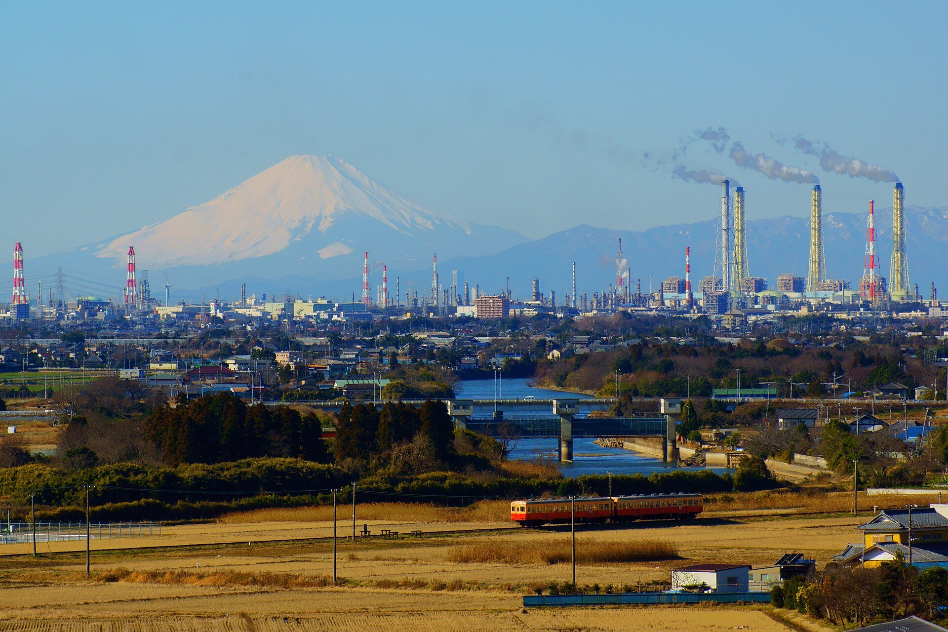 Braskem context - a large petrochemical complex with tall chimneys and Mount Fuji behind, illustrating the petrochemical industry.
