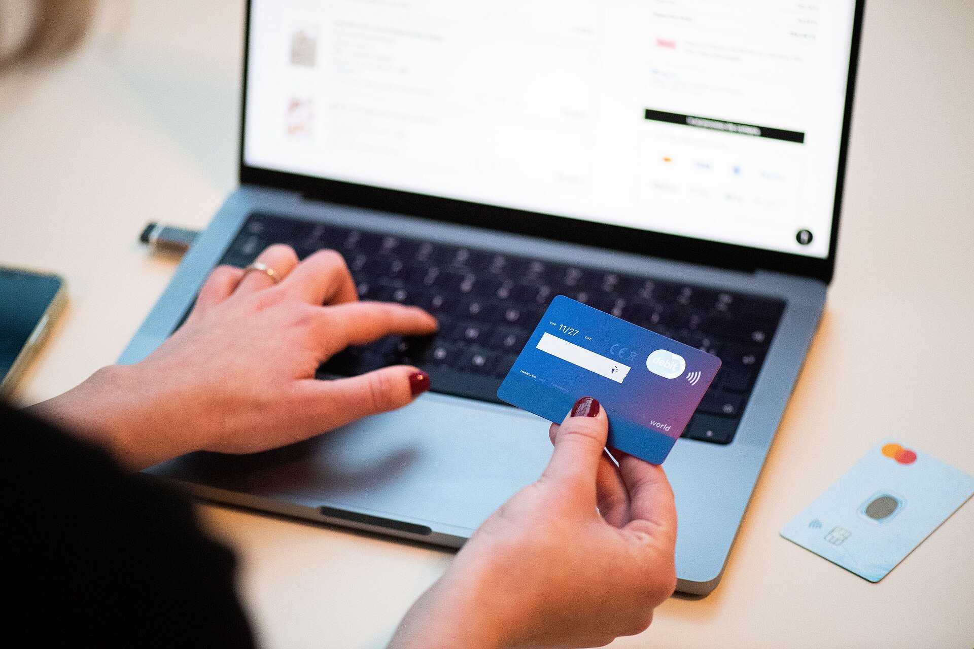 A person shopping online with a bank card and laptop, illustrating the cashback business of Méliuz, the fintech at the center of BTG Pactual's growing stake.