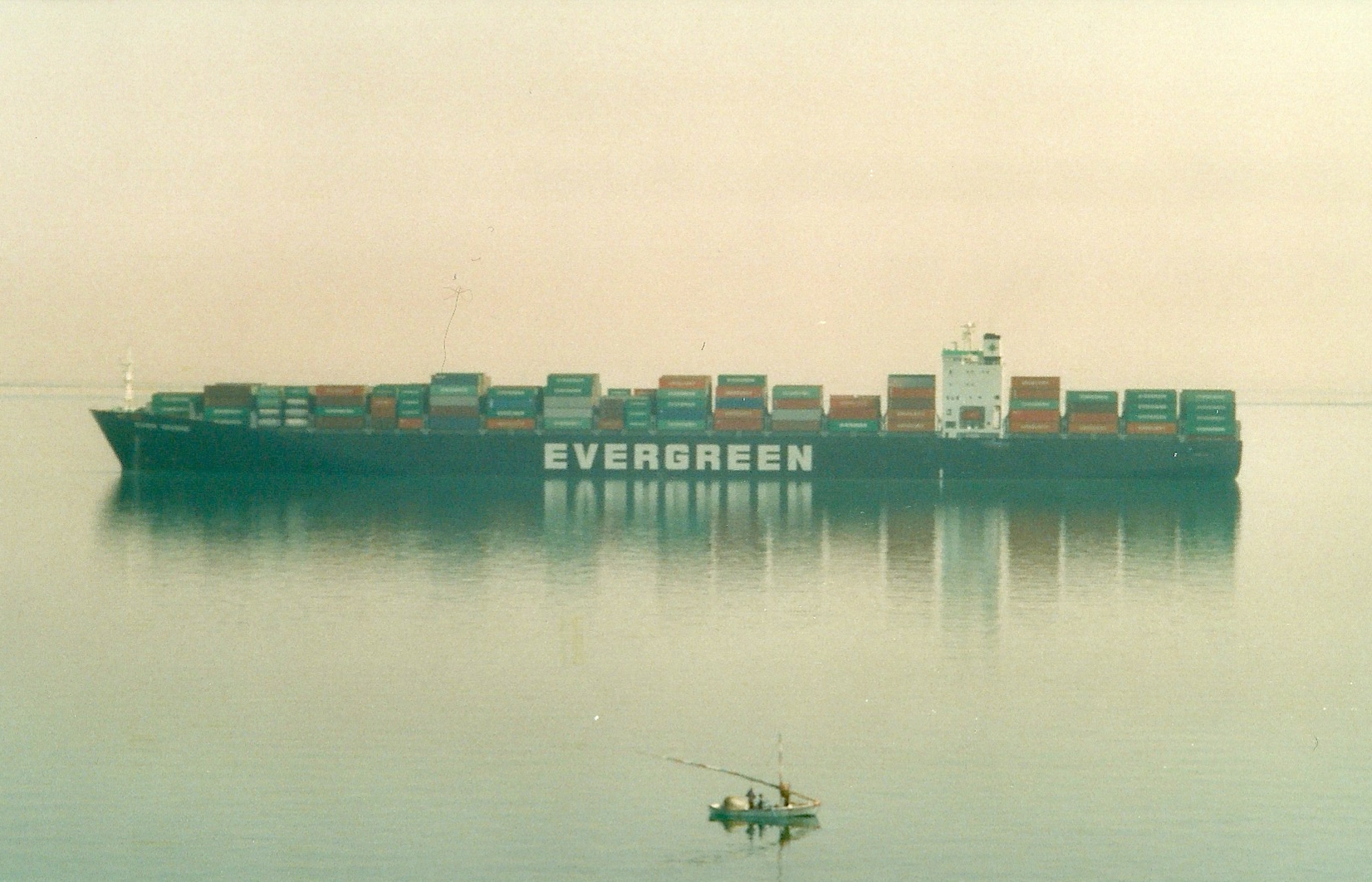 An Evergreen container ship transiting the Suez Canal, with a small fishing boat in the foreground