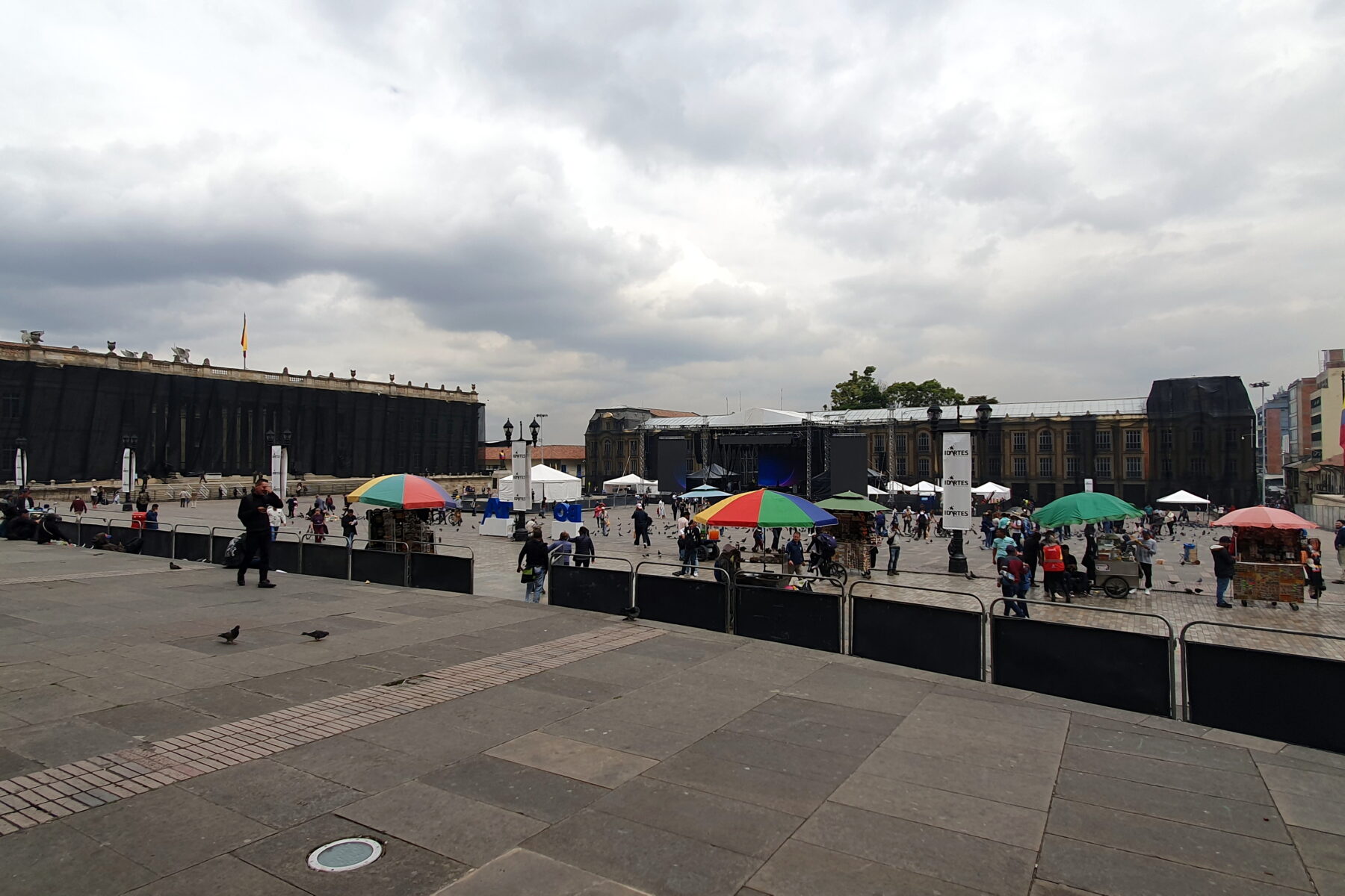 Outdoor event with stage, tents, people, and a Colombian flag