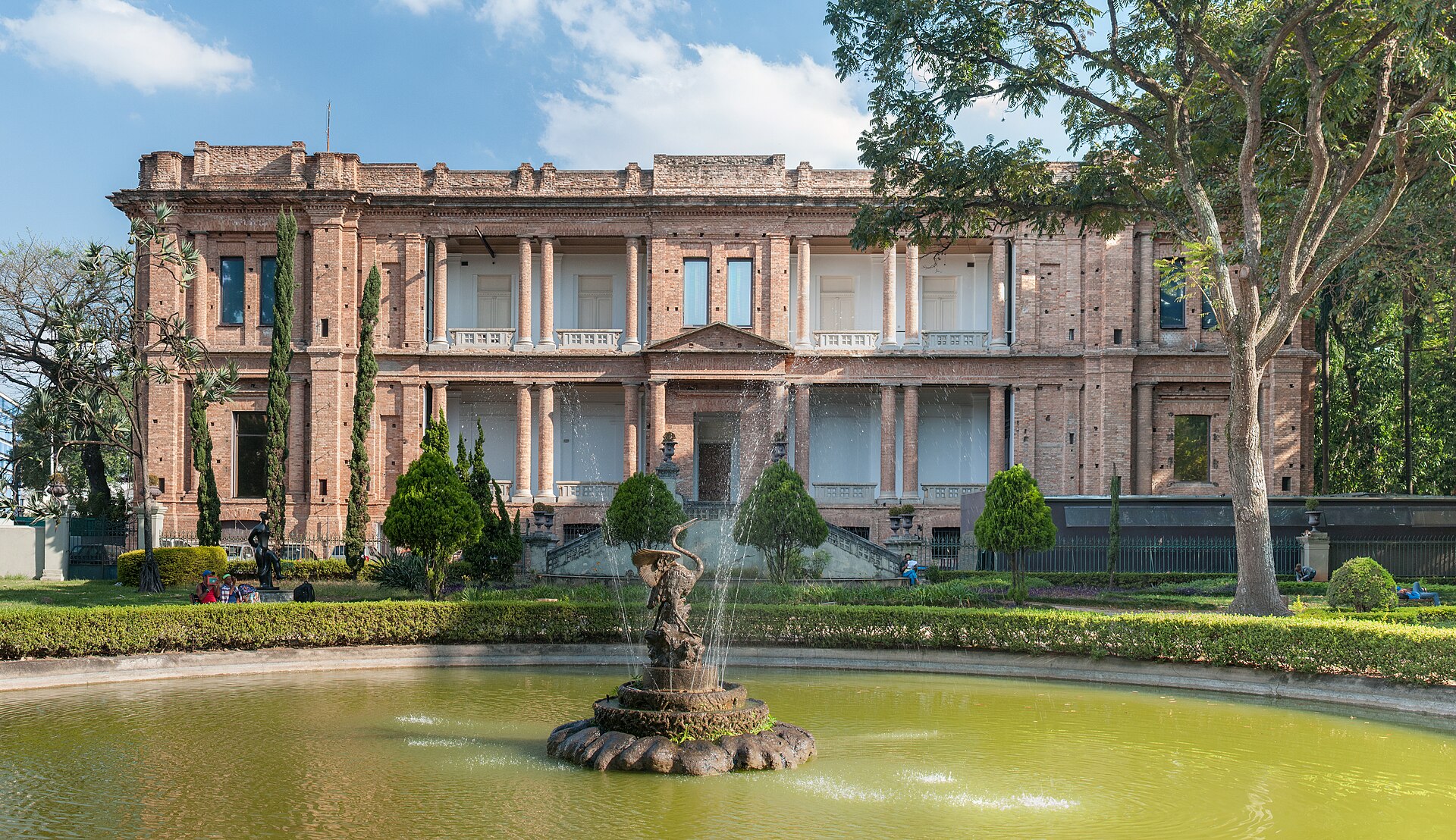 The brick facade of the Pinacoteca de São Paulo seen from the Luz park fountain