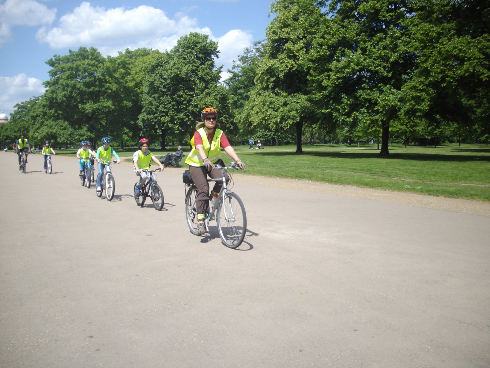 A group cycles along a park path.